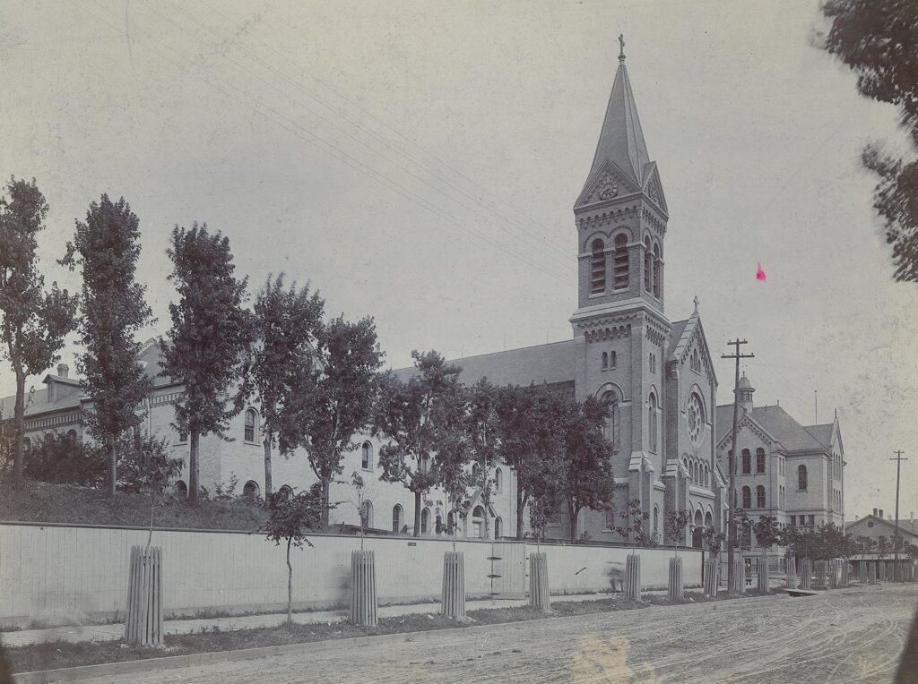 An undated black-and-white photograph showing St. Francis Church and a partially-construction St. Francis Monastery with only the east wing.